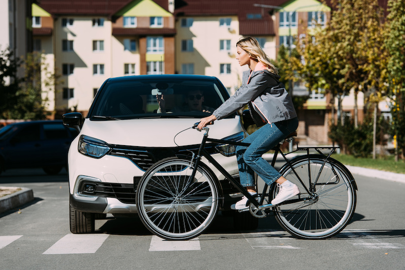 woman riding bicycle while crossing road with driver in car