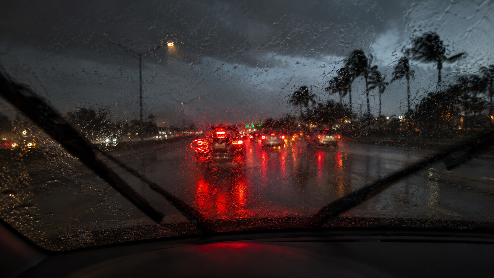 Heavy rain on a windshield with brake lights ahead during a Florida hurricane-season drive